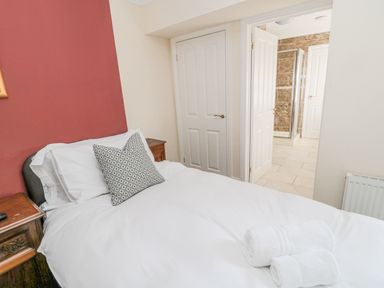 A bedroom with a double bed pillows and towels near a doorway leading to a bathroom at Jubilee House Embleton