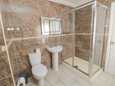 A bathroom with a toilet sink and shower enclosure at Jubilee House in Embleton