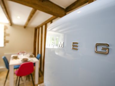 A kitchen with a smeg refrigerator and a dining table with colorful chairs at Washpool in Milton-Under-Wychwood