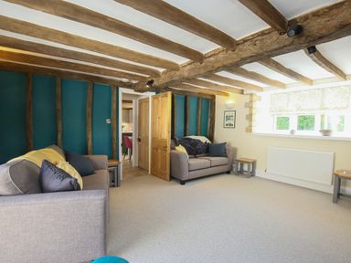 A living room with two sofas wooden beams on ceiling and walls and a window with a blind at Washpool in Milton-Under-Wychwood