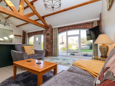A living room with gray sofas a wooden coffee table and exposed wooden beams at Plough Cottage Little Kelk near Bridlington