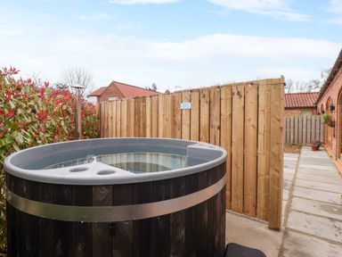 A hot tub and wooden fence in a garden at Plough Cottage Little Kelk near Bridlington