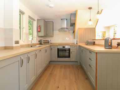 A kitchen with grey cabinets wooden countertops built in oven and stainless steel sink at 32 Trevithick in Hayle