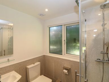 A bathroom with a toilet sink mirror window and a glass shower at 32 Trevithick in Hayle