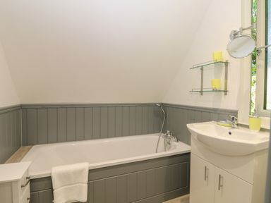 A bathroom with a bathtub a white sink with cabinet and a towel hanging over the tub at 32 Trevithick in Hayle
