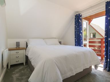 A bedroom with a double bed white bedding a bedside table with a lamp and blue curtains with stars and moons at 32 Trevithick in Hayle