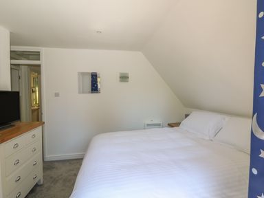 A bedroom with a double bed a chest of drawers and a television at 32 Trevithick in Hayle