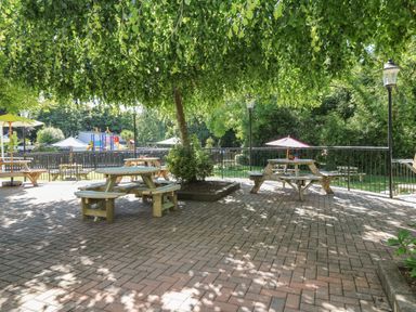 An outdoor patio area with wooden picnic tables and benches under a tree at 32 Trevithick in Hayle