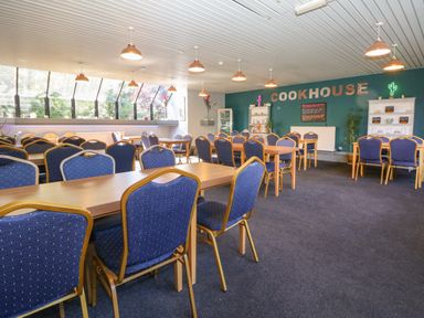A dining area with multiple tables and blue chairs with gold frames at 32 Trevithick in Hayle