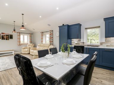 An open kitchen and dining area with a dining table set for six and a living room with beige sofas at Strawberry Stables in Iwood near Congresbury