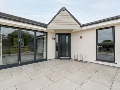The entrance area with a black front door large glass sliding doors and a window at Strawberry Stables in Iwood near Congresbury