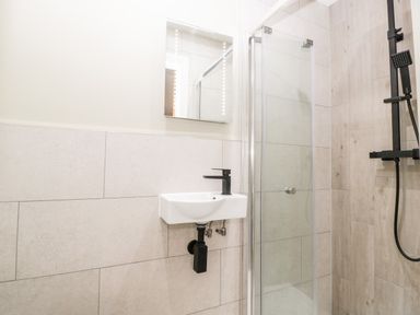 A bathroom with a wall-mounted sink a mirror a glass shower enclosure and a shower fixture at Strawberry Stables in Iwood near Congresbury