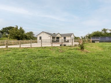 A single-story house with a fenced yard and green grass at Strawberry Stables in Iwood near Congresbury