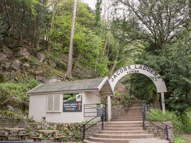 An entrance archway and stairs leading to Jacobs Ladder and Tower with a small building nearby and trees around at Strawberry Stables in Iwood near Congresbury