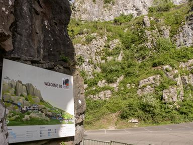 A rocky cliffside with a welcome sign for Cheddar Gorge and Cliffs and a parking area at Strawberry Stables in Iwood near Congresbury