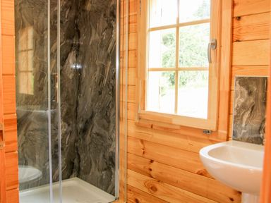 A bathroom with a glass shower enclosure a window and a white sink at Callow Fold in Dinchope near Craven Arms
