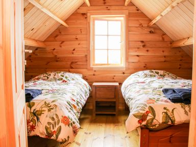 A wooden bedroom with two single beds and a window at Callow Fold in Dinchope near Craven Arms