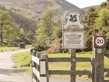 A rural landscape with road signs and green hills in the background at Carding Mill Valley