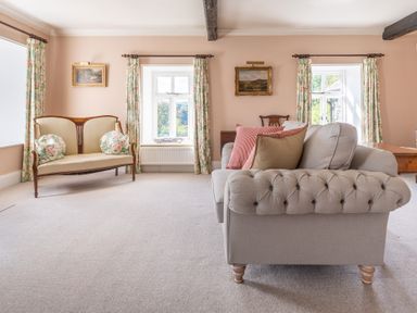A sitting room with two sofas floral curtains and landscape paintings at Field Head House in Graythwaite near Hawkshead