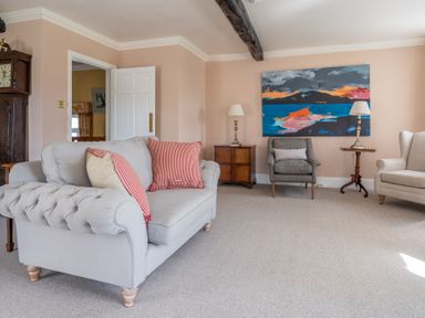 A living room with a grey sofa and armchairs two wooden side tables with lamps and an abstract painting on the wall at Field Head House in Graythwaite near Hawkshead