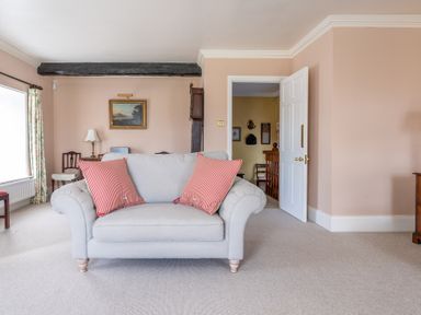 A living room with a light gray sofa with red striped cushions a painting on the wall and an open door at Field Head House Graythwaite near Hawkshead