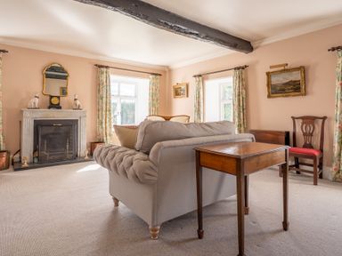A living room with a sofa table fireplace and floral curtains at Field Head House in Graythwaite near Hawkshead