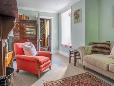 A sitting room with an orange armchair a beige sofa a wooden chest of drawers and a window seat at Field Head House Graythwaite near Hawkshead