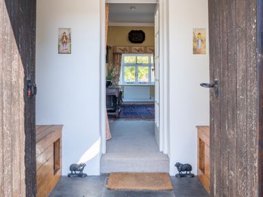 A view through an open doorway showing a hallway with a doormat and decorative sheep doorstops at Field Head House Graythwaite near Hawkshead
