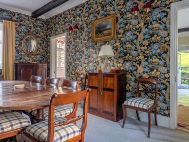 A dining room with a wooden table and chairs with checkered cushions at Field Head House in Graythwaite near Hawkshead