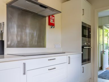 A kitchen countertop with stovetop and utensils next to built-in oven and microwave at Field Head House in Graythwaite near Hawkshead