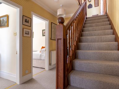 A staircase with wooden banister and carpet and a hallway with doors leading to rooms at Field Head House Graythwaite near Hawkshead