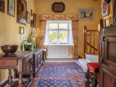 A hallway with an oriental rug wooden tables and a window with curtains at Field Head House Graythwaite near Hawkshead