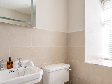 A bathroom with a white sink and toilet next to a window with blinds at Field Head House in Graythwaite near Hawkshead