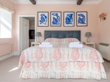 A bedroom with a patterned bedspread and four blue abstract art pieces above the bed at Field Head House in Graythwaite near Hawkshead