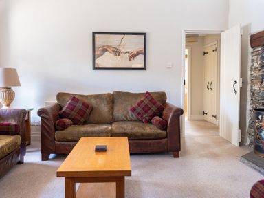 A living room with a brown sofa a wooden coffee table a lamp and a picture on the wall at Grubbings Graythwaite near Hawkshead