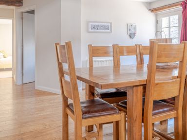 A dining area with a wooden table and six wooden chairs with leather cushions at Grubbings Graythwaite near Hawkshead