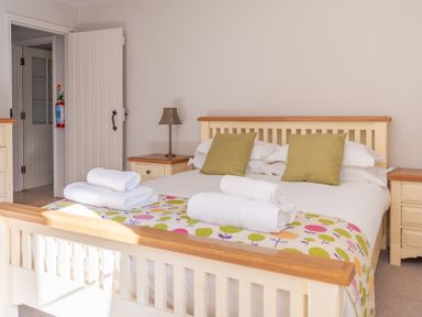 A bedroom with a bed made with white linens and green pillows and nightstands with a lamp at Grubbings Graythwaite near Hawkshead