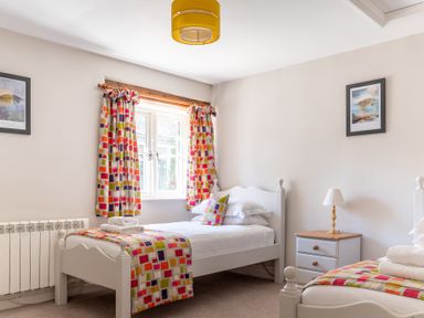 A bedroom with two single beds colorful curtains and bed runners and a bedside table with a lamp at Grubbings Graythwaite near Hawkshead