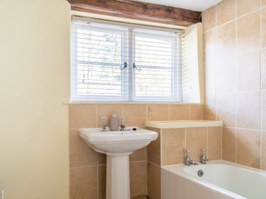 A bathroom with a pedestal sink and bathtub under a window with blinds at Grubbings Graythwaite near Hawkshead