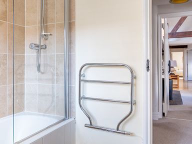 A bathroom corner with a bathtub shower and a wall-mounted towel rail at Grubbings Graythwaite near Hawkshead