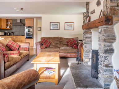 A living room with sofas and a wooden coffee table near a stone fireplace at Bull Pen Graythwaite near Hawkshead