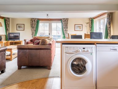 A living and dining room with leather sofas washing machine and dishwasher at Bull Pen in Graythwaite near Hawkshead