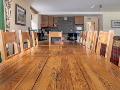 A dining table with wooden chairs in a kitchen and living room area at Bull Pen Graythwaite near Hawkshead