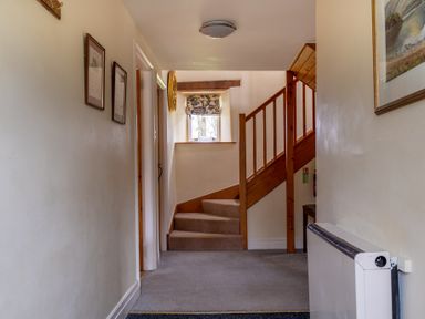 A hallway with carpeted stairs and wooden railing at Bull Pen in Graythwaite near Hawkshead