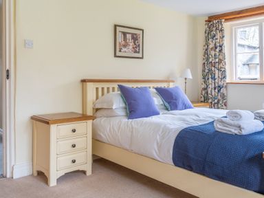 A bedroom with a bed with blue cushions and towels on it two nightstands and a window at Bull Pen in Graythwaite near Hawkshead