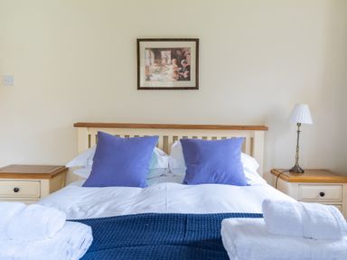 A bedroom with a double bed with blue pillows and white towels on a blanket at Bull Pen in Graythwaite near Hawkshead