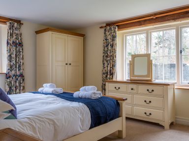 A bedroom with a bed folded towels a wardrobe and a dresser with a mirror at Bull Pen in Graythwaite near Hawkshead