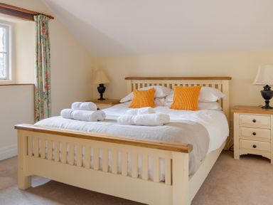A bedroom with a double bed with orange cushions and folded towels on it at Bull Pen Graythwaite near Hawkshead