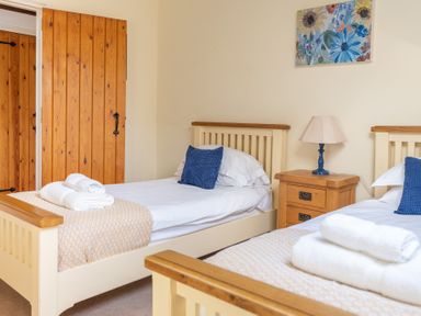 A bedroom with two single beds a bedside table and a floral painting on the wall at Bull Pen Graythwaite near Hawkshead