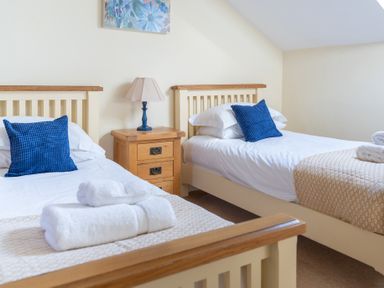 A bedroom with two single beds with blue pillows and white linens at Bull Pen in Graythwaite near Hawkshead